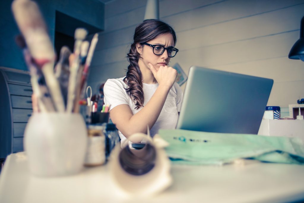 A woman looks overwhelmed over cybersecurity alerts on her laptop.